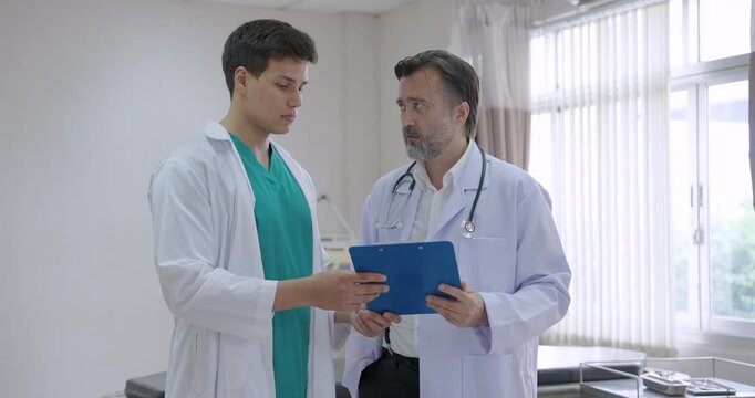 Medical professionals analyzing patient information while discussing clinical treatment plan in hospital setting showing collaboration between senior and junior doctors for accurate care