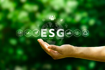 Hand holding globe with ESG letters and sustainability icons on green background, representing corporate environmental social governance strategy, responsible business growth and climate action