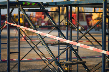 Fototapeta premium Red and white stripe barricade tape using to control danger zone in construction working site. Close-up and selective focus in foreground.