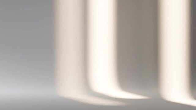 Close-up of three rounded rectangular columns with soft shadows on a plain gray background with warm lighting.