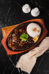 Sizzling Black Pepper Beef with Rice and Egg on a Hot Plate.