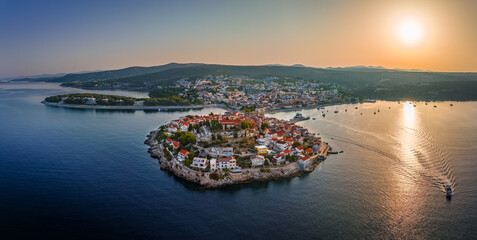 Primosten, Croatia - Aerial panoramic view of Primosten peninsula and old town on a sunny summer morning in Dalmatia, Croatia. Blue and golden sky at sunrise with motorboat going on the Adriatic sea