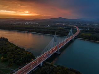 Obraz premium Budapest, Hungary - Aerial view of the cable-stayed Megyeri Bridge over River Danube at dusk with beautiful dramatic golden sunset sky and Buda Hills at background