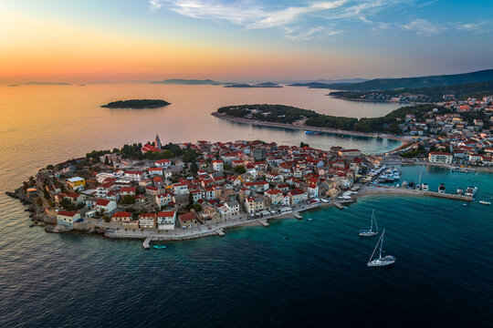 Primosten, Croatia - Aerial view of Primosten peninsula and old town on a sunny summer afternoon in Dalmatia. Yacht marina, sailboats, golden sky at sunset by the Adriatic sea coast - Powered by Adobe