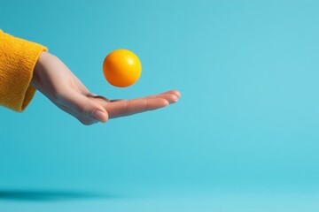 Hand holding a floating orange against a blue background.