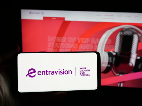 Stuttgart, Germany - 12-11-2025: Person holding smartphone with logo of US company Entravision Communications Corp. on screen in front of website. Focus on phone display.