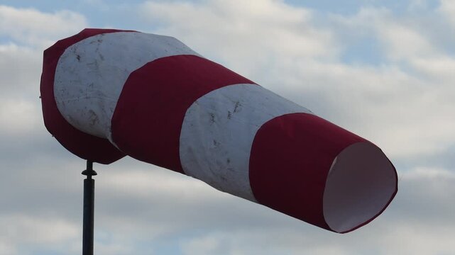 Red and white strip windsock on blue sky background. The equipment using to indication windy speed and direction.