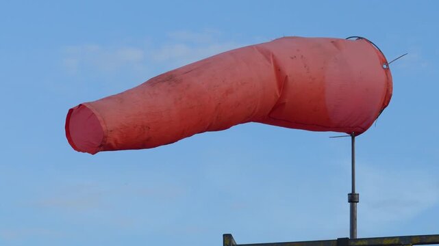 An orange windsock on blue sky background. The equipment using to indication windy speed and direction.