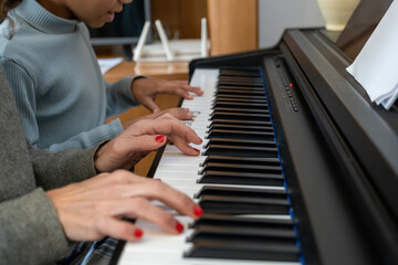 Teacher and student hands playing piano keys together, learning music and melody. Education, practice, and skill development © Manuel