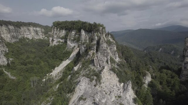 Aerial drone shot circling the Sairme Pillars in Lechkhumi, Georgia, capturing towering rock formations from all sides amid green hills and untouched Caucasus nature. High-quality 4K footage.