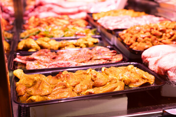 Meat department of store sells chicken meat marinated with addition of curry seasoning.