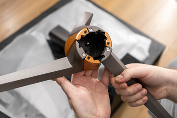 A person carefully unboxes and assembles a sophisticated grey and bronze appliance component, showcasing modern innovative design and smart home technology integration