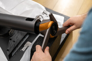 A person's hands skillfully assembling a modern monitor stand featuring sleek design, distinctive orange accents, and precise components for an optimized workspace setup