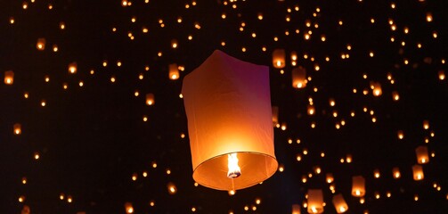 Sky lantern floating in the dark night sky, Tourist floating sky lanterns, Sky lanterns floating on night of Yi Peng, Loy Krathong Festival or Yi Peng Festival in Chiang Mai Thailand. © Kalyakan