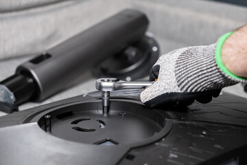 Gloved hand uses ratchet wrench to secure component on electronic device, illustrating detailed...