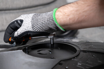 Worker's gloved hand expertly operates a precise ratchet wrench, meticulously assembling a sophisticated electronic device, highlighting technical skill and detailed repair