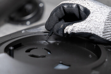 Professionals gloved hand precisely inserting a small screw standoff into a complex black electronic component, showcasing meticulous assembly and technical service