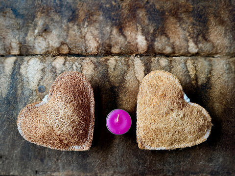 Two pieces of Luffa heart shape and pink cancle put on vintage wooden board,