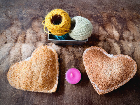 Two pieces of Luffa heart shape,candle and yarn box put on vintage wooden board,