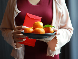 Lunar new year, An Asian woman wearing a red shirt is carrying a basket of mandarin orange for symbolizes good luck and wealth