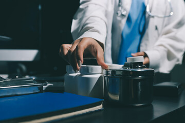 Two doctors and a female nurse meet at a table in the hospital, collaborating on medical tasks using laptops and computers