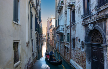 the gondolier with his gondola in a narrow canal in Venice © corradobarattaphotos