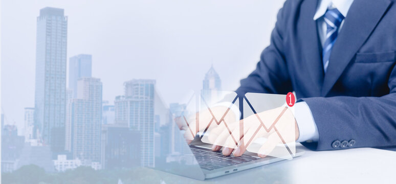 Businessman typing on laptop with email notification icon corporate communication and online messaging concept digital inbox alert business technology professional email marketing over city background - Powered by Adobe