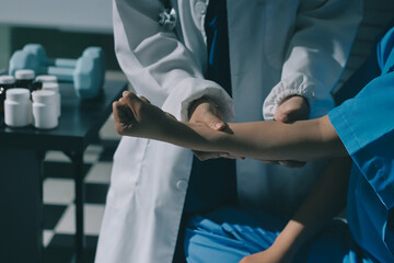 Doctor examining patient's elbow in hospital room