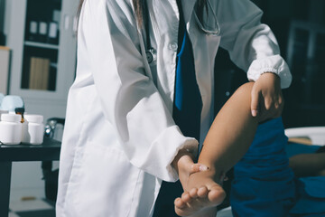 Doctor examining and supporting injured ankle of female patient in hospital room, providing medical assistance and treatment for sprain or fracture