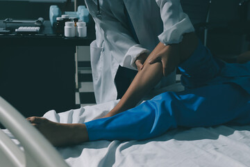 Doctor examining and supporting injured ankle of female patient in hospital room, providing medical assistance and treatment for sprain or fracture