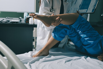 Doctor examining and supporting injured ankle of female patient in hospital room, providing medical assistance and treatment for sprain or fracture