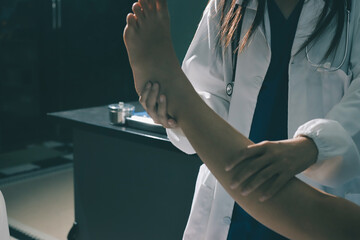 Doctor examining and supporting injured ankle of female patient in hospital room, providing medical assistance and treatment for sprain or fracture