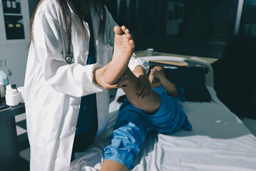 Doctor examining and supporting injured ankle of female patient in hospital room, providing medical assistance and treatment for sprain or fracture