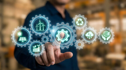 Industrial engineer hand touching virtual gear mechanism with green energy icons,concept of sustainable manufacturing,eco friendly technology,circular economy,environmental saving.