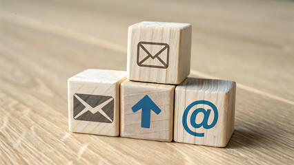 Wooden Blocks with Communication Icons: Email, Arrow Up, and At Symbol Stacked on Table