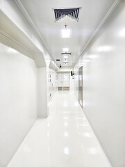 A long, brightly lit white hallway with a polished floor and ceiling lights.
