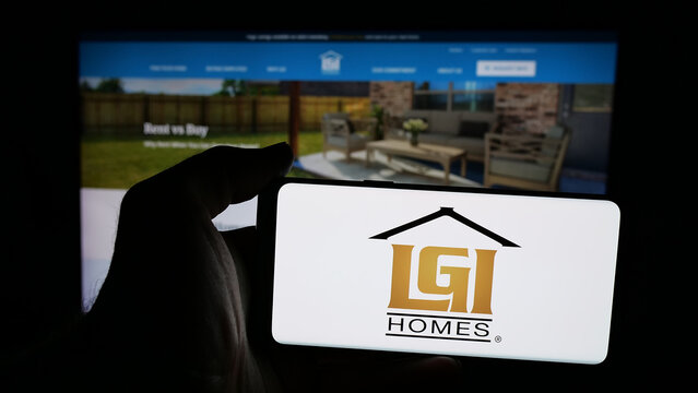 Stuttgart, Germany - 12-12-2025: Person holding mobile phone with logo of US homebuilding company LGI Homes Inc. on screen in front of web page. Focus on phone display.
