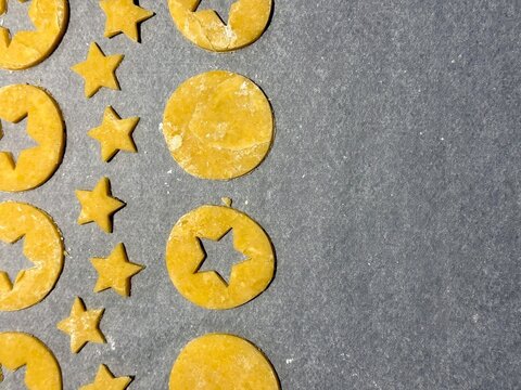 Homemade Alsatian bredele cookie dough cut into star and round shapes on parchment-lined baking tray, lightly floured and ready to bake for Christmas holiday treats