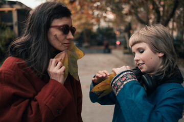Mom and daughter having fun together at walk in autumn city