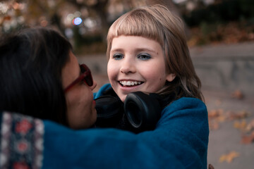 Mom and daughter having fun together and hugging outdoors in city