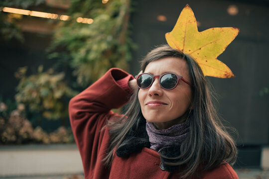 Happy woman holds golden sycamore leaf to her head like a crown