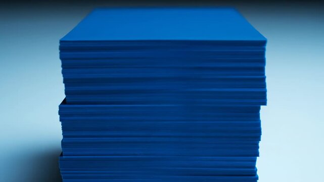 Extreme slow motion vertical tilt focusing on two perfectly uniform stacks of blank blue cards against a contrasting minimalist blue background smooth camera, finance, data