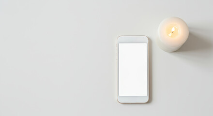 A serene flat lay featuring a phone next to a candle on a clean, white surface background.