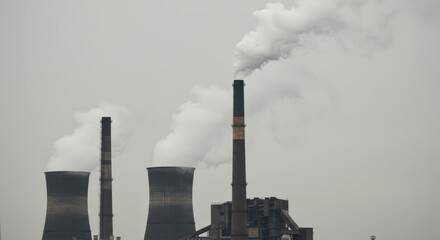 Industrial complex releases clouds of smoke into the atmosphere, impacting environment.