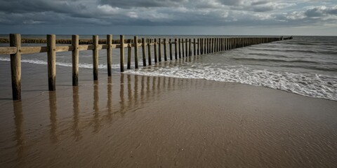 Fototapeta premium Holzpfeiler am Strand unter dramatischem Himmel