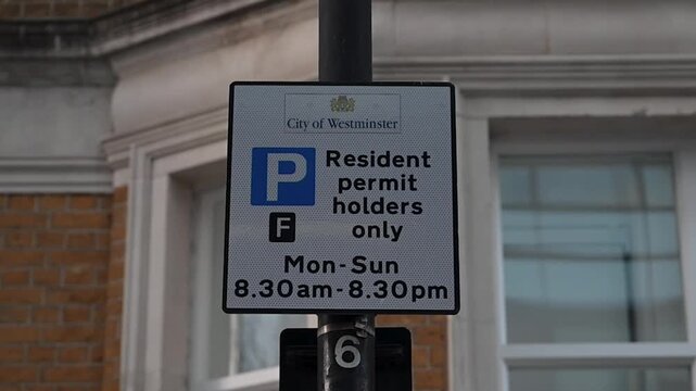 Street parking sign stating resident permit holders only in the City of Westminster showing controlled local parking rules and urban regulation.