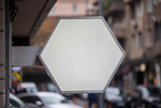 Blank Hexagonal Shop Sign Mounted Outside A Building With Cars In The Background