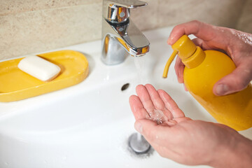 Human hands are turning the home faucet on and washing it with soap and clean tap water for good...