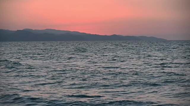 Breathtaking 4K footage of a vivid sunset over the Cyprus coastline. Captures the sun setting over the Mediterranean Sea with silhouetted mountains (Troodos/Pentadaktylos) in the frame. Ideal for trav