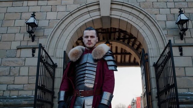 Medieval knight stands at castle gate in armor with fur collar. Knight wearing medieval armor near stone castle arch. Warrior with fur at castle gate. Medieval warrior stands at fortress entrance.